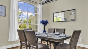 Une salle à manger avec une grande fenêtre, un miroir et une table dressée pour quatre personnes.