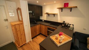 A compact kitchen with wooden cabinets, a black countertop, and a dining area with a tray of cups and a kettle. - 50m from ski slopes, 1st floor, view mountain, balcony, tv, ski locker, 34m², Valmorel (Valmorel)