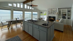 Une cuisine spacieuse dotée d’un grand îlot central, d’une cheminée et offrant une vue sur l’océan.