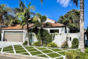 A residential house with a garage, surrounded by palm trees and well-maintained lawn.
