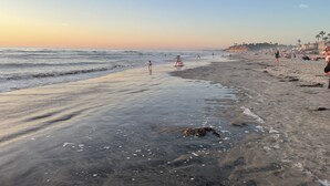 A beach with people engaging in various activities, a clear sky, and a calm sea. - 2 minute walk to Del Mar Beach! (Del Mar)