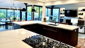 A modern kitchen with a large island, a gas stove, and a dining area with a table and chairs. - 2 minute walk to Del Mar Beach! (Del Mar)