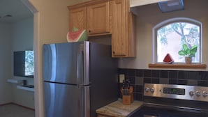 A kitchen with a stainless steel refrigerator, an oven, and a window with a plant. - Charming Casita, Old World look with all the modern conveniences. (Rio Rancho)