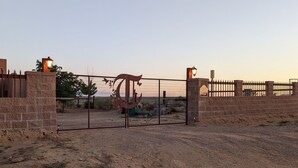 A gated entrance with a metal gate and brick walls, a street lamp, and a clear sky. - Charming Casita, Old World look with all the modern conveniences. (Rio Rancho)