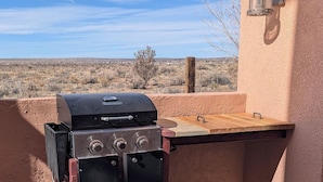 A barbecue grill with a wooden countertop and a sink attached to a building with a view of a desert landscape. - Charming Casita, Old World look with all the modern conveniences. (Rio Rancho)