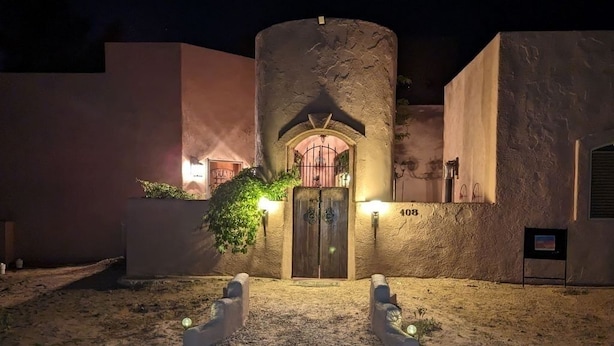 A building with a stone entrance, a number '408' on the wall, and a small garden area with a pathway leading to the entrance. - Charming Casita, Old World look with all the modern conveniences. (Rio Rancho)