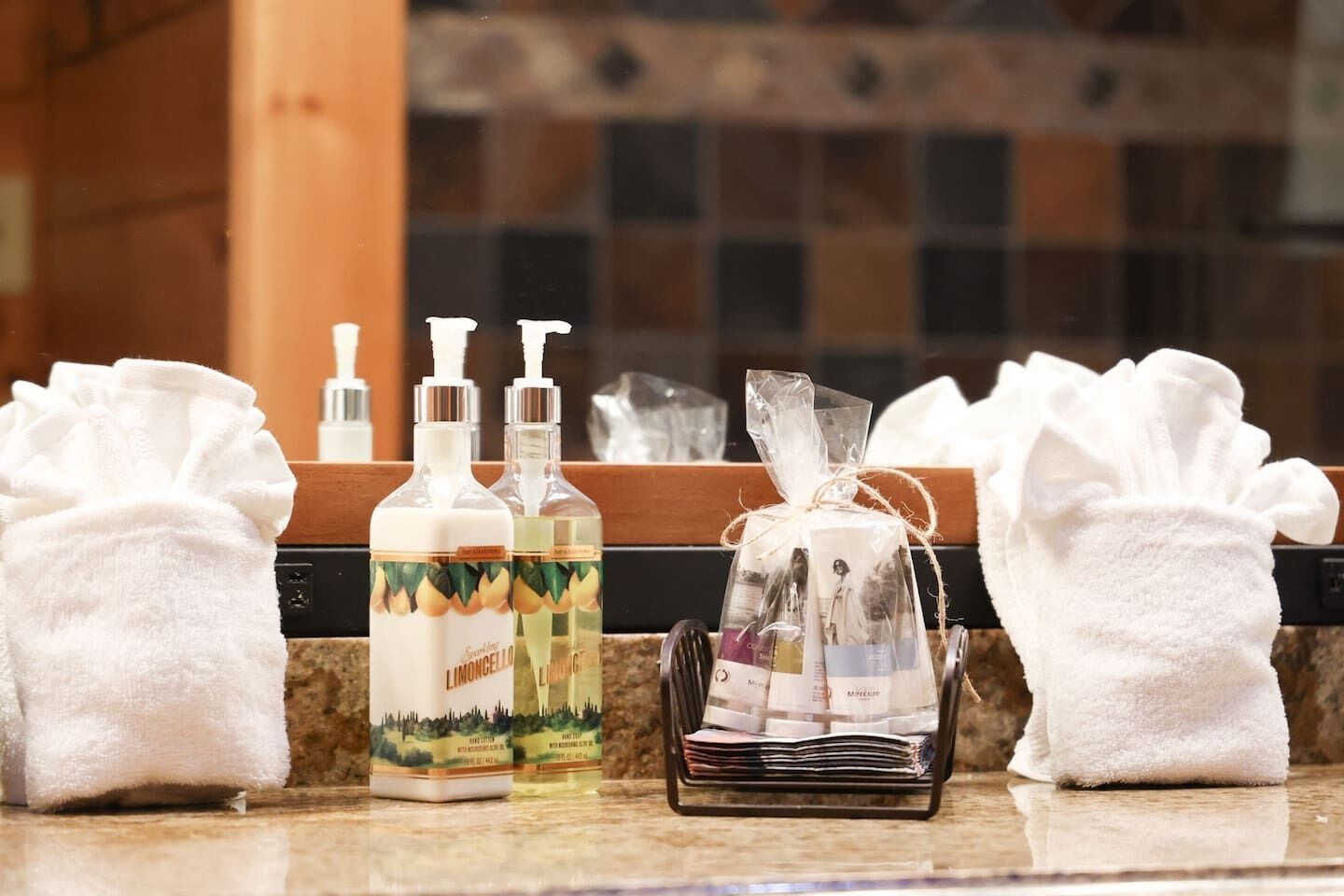Un meuble-lavabo de salle de bain avec des articles de toilette, notamment du savon pour les mains, une lotion et un petit sac cadeau.