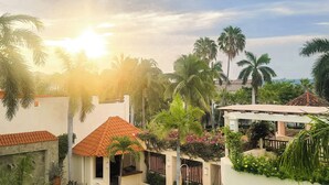 A pool area with a clear view of the pool, surrounding palm trees, and a building with a tiled roof. - Huatulco beauty in Chahue Bay. Large family condo with ocean and mountain views (Chahue)