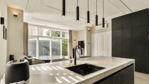 A modern kitchen with a large island, dark cabinetry, and pendant lighting. - Luxury Rijksmuseum house (Amsterdam)