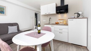 A compact living space with a kitchenette, a dining area, and a sofa. - KATARINA One-Bedroom Apartment with Terrace 2 (Rovinj)