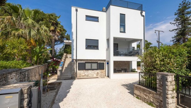 A modern two-story building with a white facade, a balcony on the upper floor, and a gravel driveway leading to the entrance. - KATARINA One-Bedroom Apartment with Terrace 2 (Rovinj)