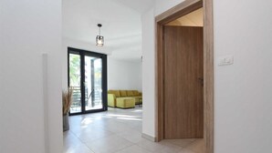 A hallway with a sliding glass door leading to a balcony, a wooden door, and a yellow sofa.