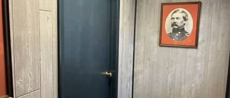 A room with a dark blue door, a framed picture on the wall, and a wooden floor.