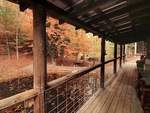 Eine Holzterrasse mit Blick auf einen Fluss, umgeben von Herbstlaub.