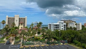 A hotel with a prominent tower, a parking lot, and a view of the ocean.