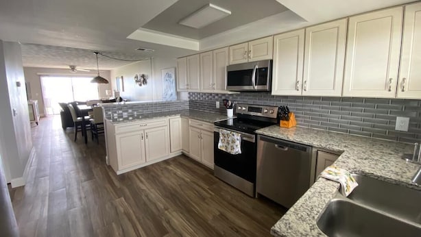 A modern kitchen with granite countertops, stainless steel appliances, and white cabinetry.