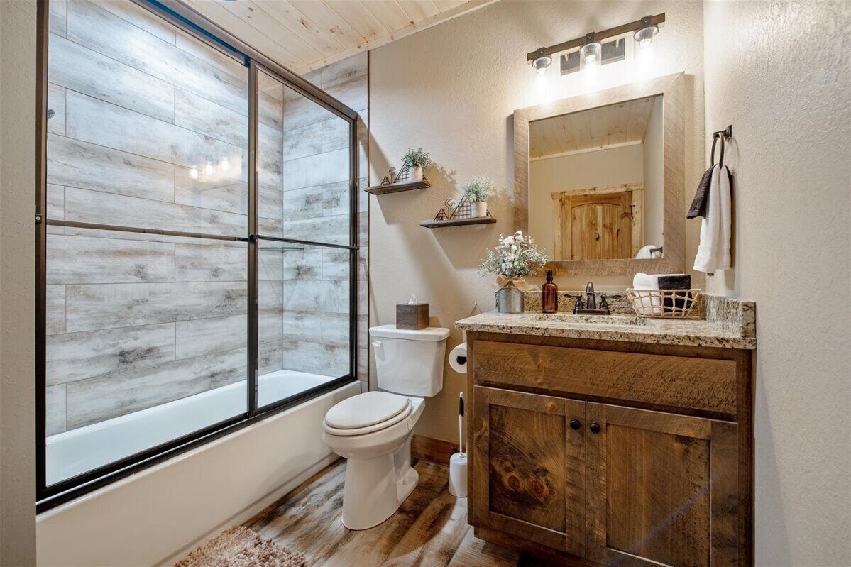 A bathroom with a large window, wooden vanity, and a mirror.