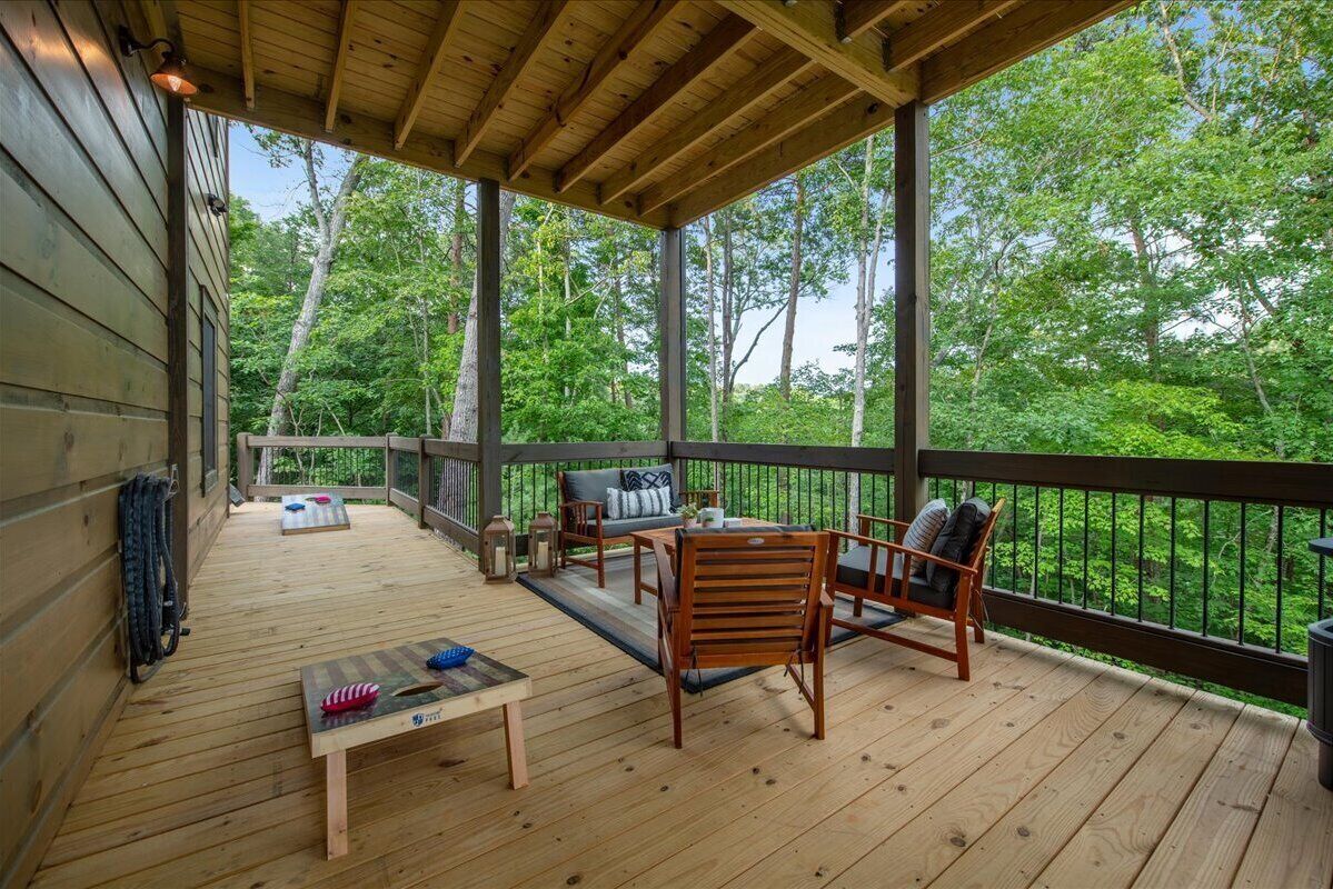 A wooden deck with outdoor furniture and a view of the forest.