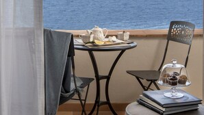 Ein Balkon mit Tisch, der für Tee gedeckt ist, einem Stuhl und Blick aufs Meer.