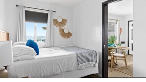 Een moderne slaapkamer met een bed, een bureau en uitzicht op zee.