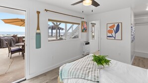 A bedroom with a bed, a ceiling fan, a window with a view of the beach, and a door leading to a balcony. - Lower Level Pet Friendly Oceanfront Studio P925-3 (Oceanside)