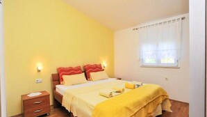 Ein Schlafzimmer mit einem Bett, Nachttischen, einem Fenster mit Vorhängen und Holzboden.