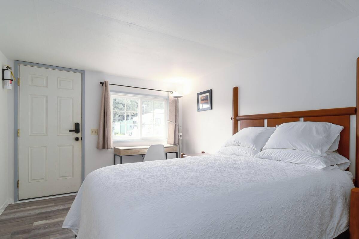 A bedroom with a bed, a desk, and a chair.