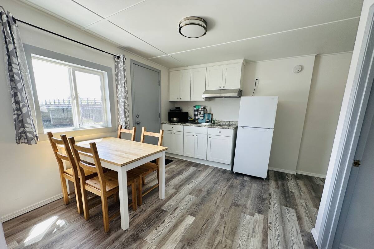 A compact kitchen with a dining table, white cabinets, and a refrigerator.