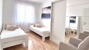 A modern, well-lit bedroom with a bed, a sofa, and a chair. - Apartment Lana - Two Bedroom Apartment with Terrace and Sea View (Dubrovnik)