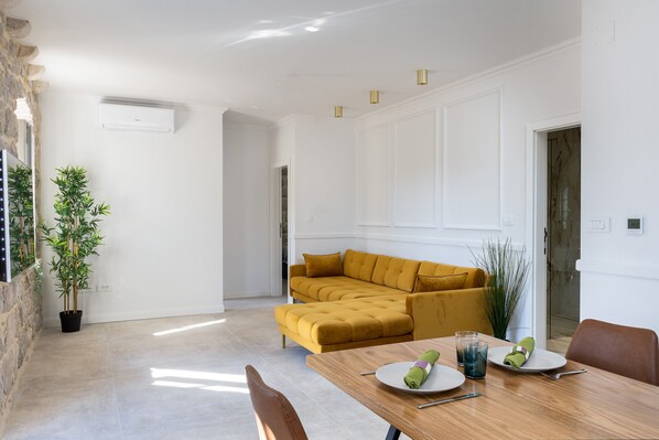 Un comedor con una mesa de madera, un sofá amarillo y una planta en maceta.