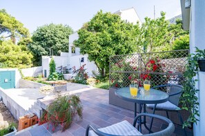 A patio with a round table and chairs, surrounded by a garden with various plants and flowers. - Apartments Green Garden - Studio with Terrace (Dubrovnik)