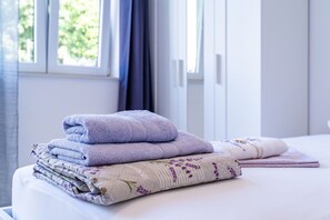 Una cama bien hecha con toallas dobladas y una manta estampada con motivos florales.