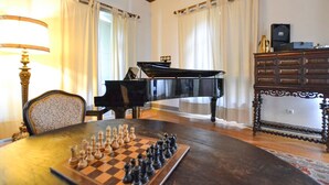 Une pièce avec un grand piano, un jeu d’échecs et une table en bois.
