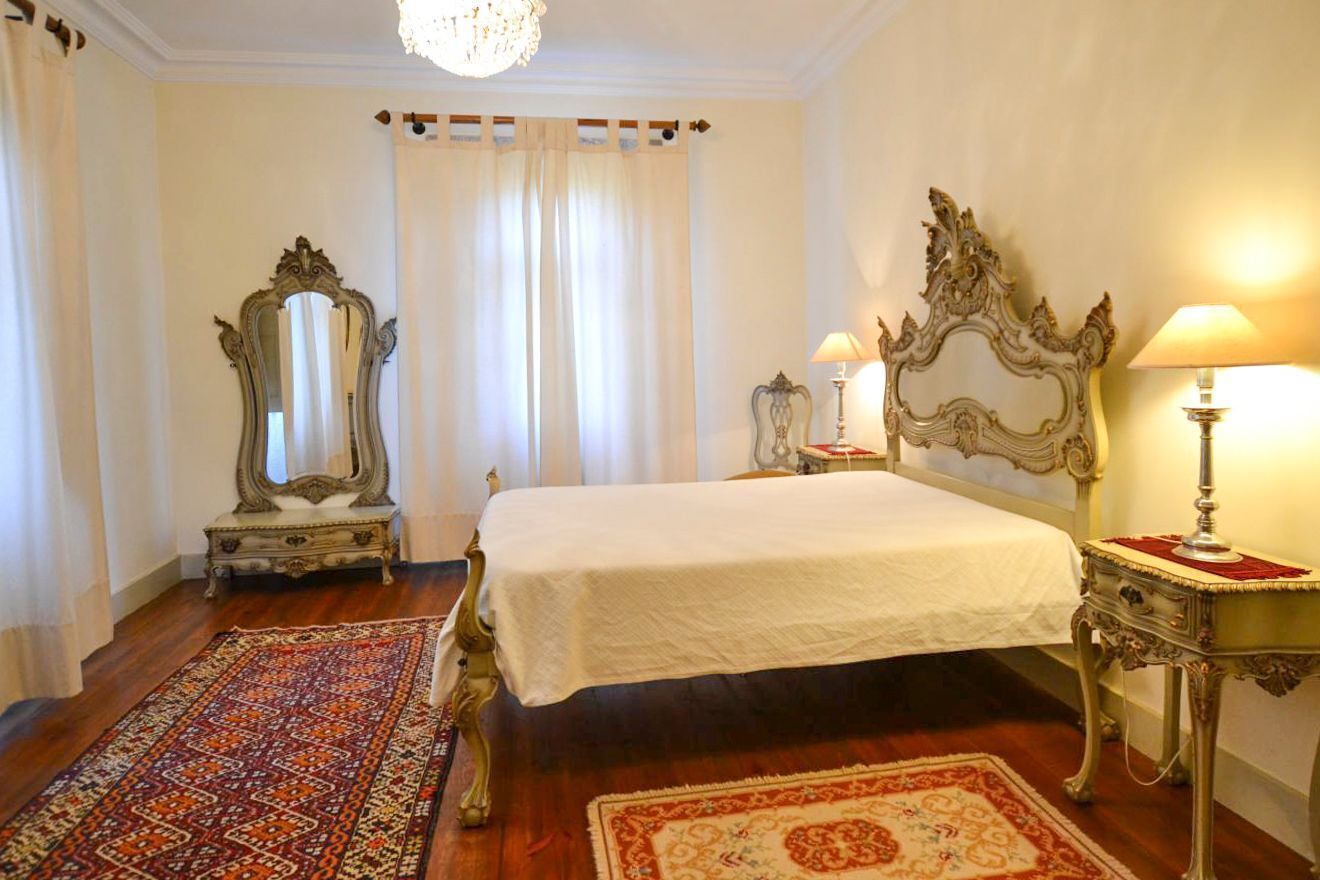 A bedroom with a large bed, ornate furniture, and a decorative rug.
