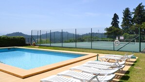 A swimming pool with a view of mountains, surrounded by a fence and a tennis court. - Casa Benedita - Six Bedroom Villa, Sleeps 12 (Abade de Neiva)