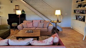 A living room with a staircase, a sofa, a coffee table, and a bookshelf.