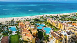 Een resort met meerdere zwembaden, een strand en uitzicht op de oceaan.