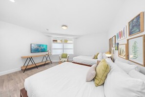 A bedroom with a large bed, a desk, a chair, and a window. - Glamorous 2-BR Beachfront Condo w/Balcony in Aruba (Noord)