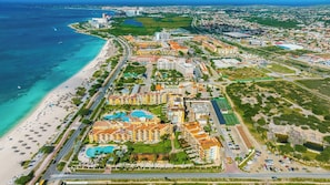 A coastal resort with multiple hotel buildings, a beach, and a marina.