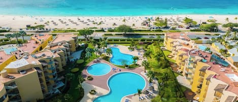 Un resort con múltiples piscinas, playa y vistas al océano.
