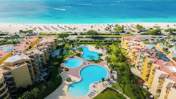 A resort with multiple swimming pools, a beach, and a view of the ocean.