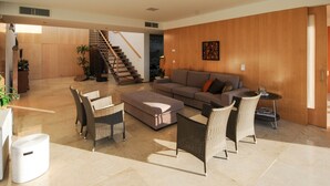 A spacious living area with a sofa, chairs, a coffee table, and a staircase leading to another room.