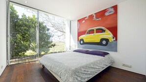 A bedroom with a bed, a large window, and a painting of a yellow car. - Caminha Views - Two Bedroom Villa, Sleeps 4 (Moledo)