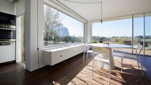 A modern kitchen with built-in appliances, a large window, and a dining area with a view. - Caminha Views - Two Bedroom Villa, Sleeps 4 (Moledo)