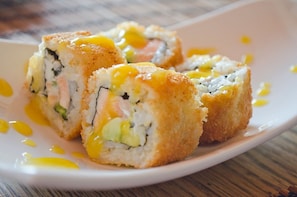 A plate of sushi rolls with a creamy sauce.