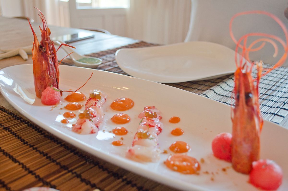 A seafood dish on a white plate with shrimp and cherry tomatoes.