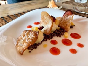A dessert plate with a pastry, ice cream, and red sauce on a white plate.