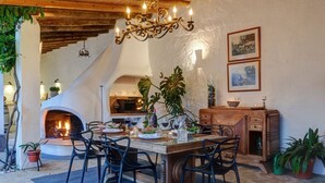 Un coin repas rustique avec une cheminée en pierre, des meubles en bois et des plantes en pot.
