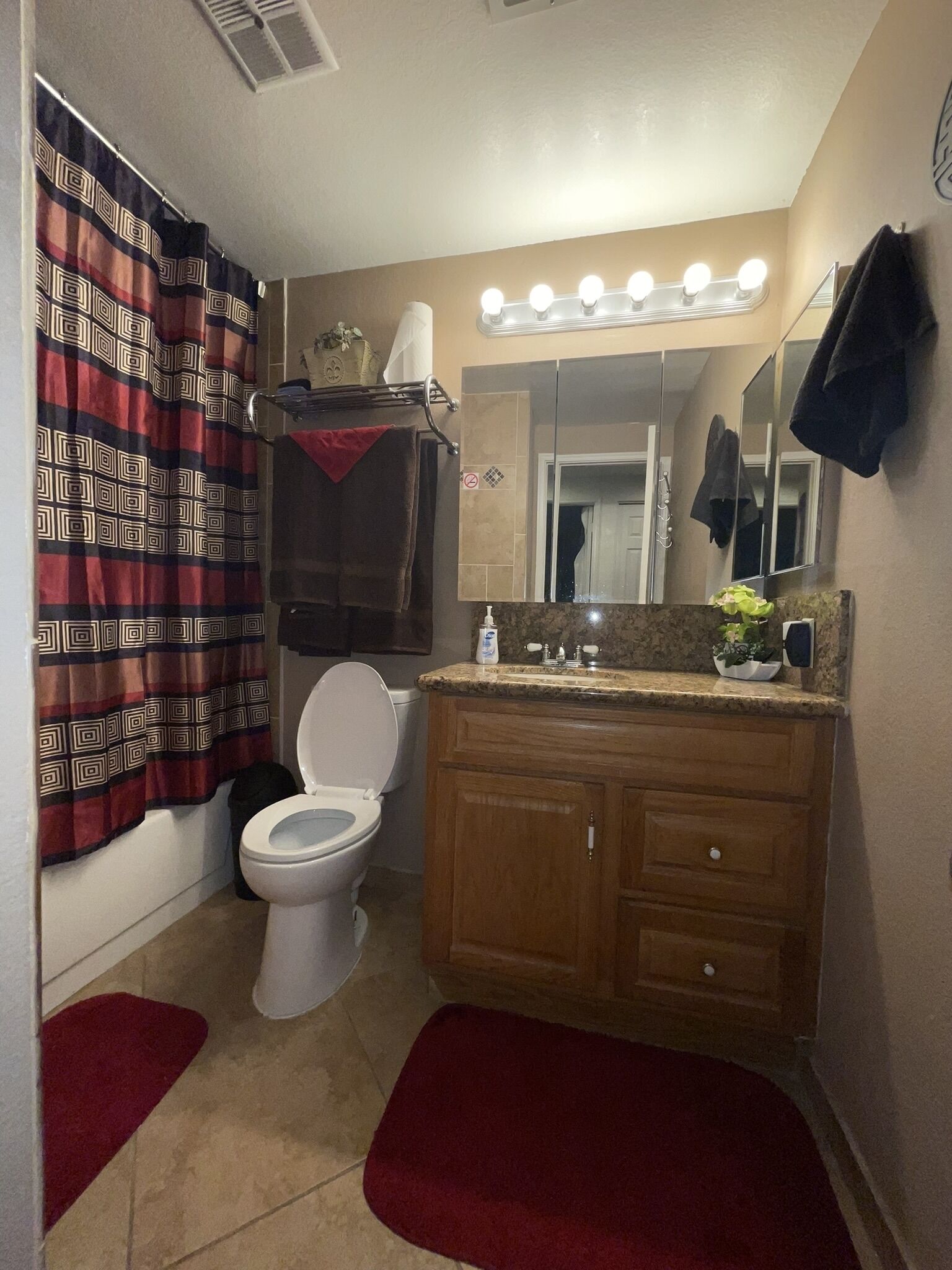 A bathroom with a toilet, vanity, mirror, and shower curtain.