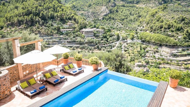 A poolside area with lounge chairs and umbrellas, overlooking a mountainous landscape. - Can Marta - Four Bedroom Apartment, Sleeps 8 (Deya)